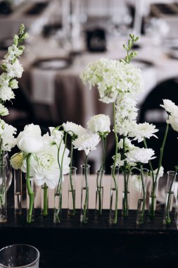 Vazolarda çiçekler olan bir düğün masası.