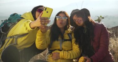Dağda gülümseyen Meksikalı kızlar selfie çeker.