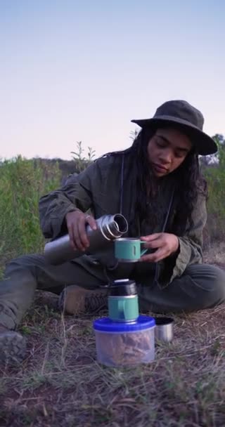 墨西哥野营女孩把咖啡从他的热水瓶倒进杯子里的垂直录像 — 图库视频影像