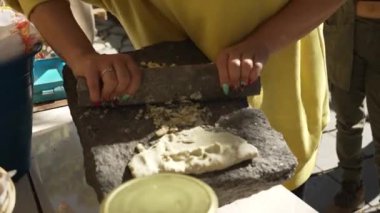 Tortillalar için nixtamal yapmaya çalışan süslü genç bir kız. Geleneksel Meksika usulü bir molcajete ile.