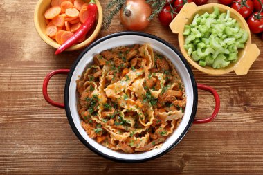 Tahta arka planda etli ve sebzeli makarna.