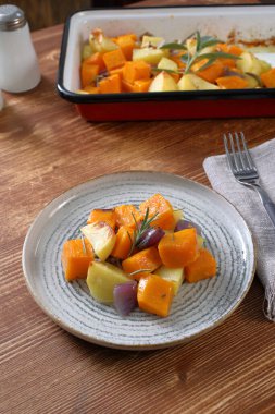 Beyaz tabakta sebzeli ve baharatlı fırında patates.