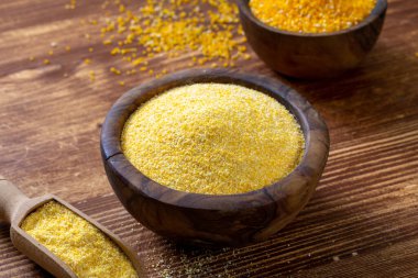 Ahşap arka planda kasede çiğ darı