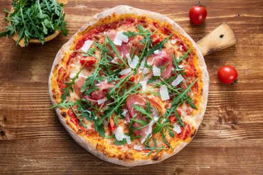 pizza with salami, tomatoes, cheese and basil on wooden background
