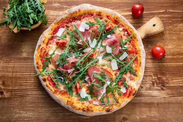 pizza with salami, tomatoes, cheese and basil on wooden background