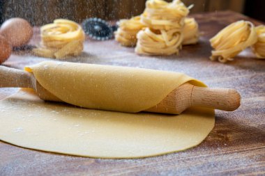 homemade pasta with flour and rolling pin on wooden table