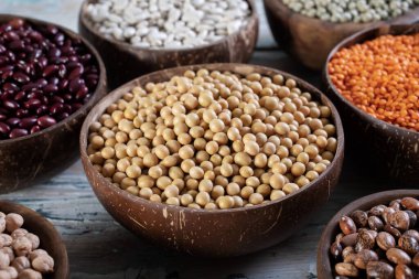 Kurutulmuş soya ve ahşap arka planda fasulye kaseleri.
