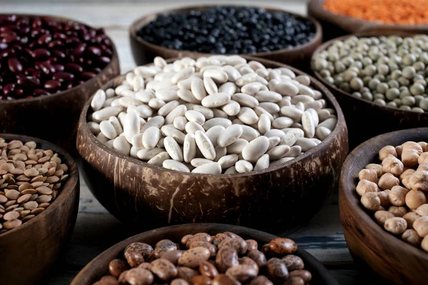 白い豆は木製のボウルにさまざまな種類のマメ科植物 — ストック写真