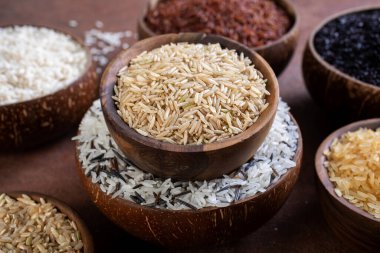 Koyu arkaplanda, ahşap kasede çiğ pirinç, yakın plan görüş.