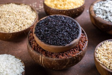 Gri arka planda, ahşap kasede siyah pirinç. en üstteki görünüm.