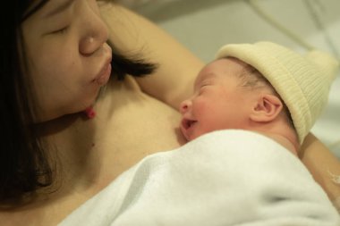 Doğumdan hemen sonra, Asya kökenli, beyaz, tapılası bebek derisi tutan bir kadının hayat tarzı. Yeni bir hayat ve ebeveynlik kavramında hastane yatağında mutlu bir şekilde yatması.