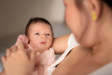 Genç ve mutlu Asyalı Çinli kadın, yeni doğmuş bebeğini şefkatle kucağına aldı. Annesi ve kızı sevgi ve ilgi kavramlarıyla.