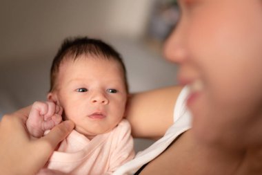 Genç ve mutlu Asyalı Çinli kadın, yeni doğmuş bebeğini şefkatle kucağına aldı. Annesi ve kızı sevgi ve ilgi kavramlarıyla.
