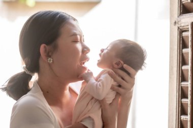 Genç ve mutlu Asyalı bir kadının hayat tarzı. Sevecen bir şekilde kucağında yeni doğmuş bebeğini taşıyor. Annesi ve kızı sevgi ve ilgi dolu.