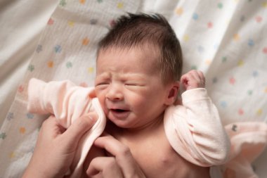 Anne elleri bebek bezi ve kıyafetlerini değiştirerek hayata döndükten günler sonra tatlı bir yüz ifadesiyle karışık Asyalı beyaz kökenli güzel ve tapılası yeni doğmuş bebeğe dönüşüyor.