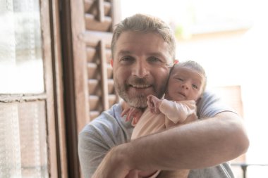 Genç ve mutlu bir adamın şefkatle kucağına aldığı bir hayat fotoğrafı. Sevecen bir şekilde kucağına yeni doğmuş bir kız bebek, baba ve kız. Sevgi ve ilgi kavramı.