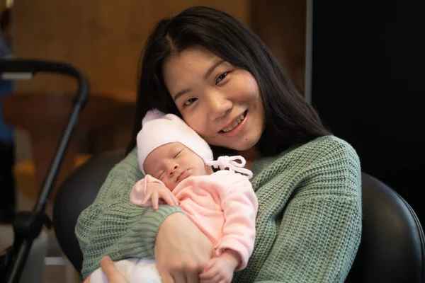 young happy and attractive Asian Korean woman holding her adorable newborn baby girl in her arms sweet and tender in parenting and mother love concept