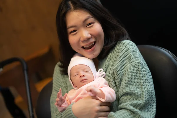 young happy and attractive Asian Korean woman holding her adorable newborn baby girl in her arms sweet and tender in parenting and mother love concept