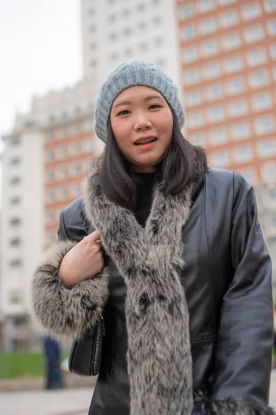 身穿皮大衣 头戴贝尼帽的年轻 美丽的亚裔中国妇女在城市商业区散步时的城市画像 — 图库照片