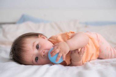 8 aylık mutlu ve güzel bebek portresi Asyalı beyaz ırkın yatakta top oynaması ve etrafı keşfe çıkması. 