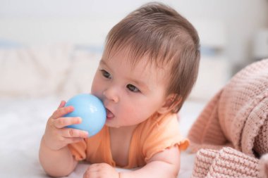 8 aylık mutlu ve güzel bebek portresi Asyalı beyaz ırkın yatakta top oynaması ve etrafı keşfe çıkması. 