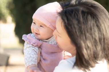 Genç bir Asyalı anne olarak saf neşe, küçük kızıyla sevgi dolu bir şekilde oynayarak, kalıcı bir sevgi bağı yaratıyor. Annelik güzelliği ve çocukluk masumiyeti.