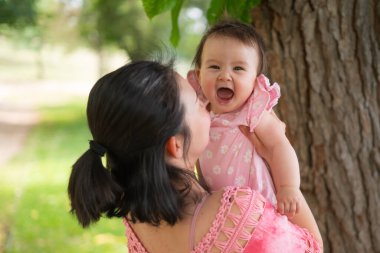 Asyalı anne ve küçük çocuk. Genç, mutlu ve güzel Koreli kadın. Şehir parkında sevimli ve neşeli bir kızla oynuyorlar.