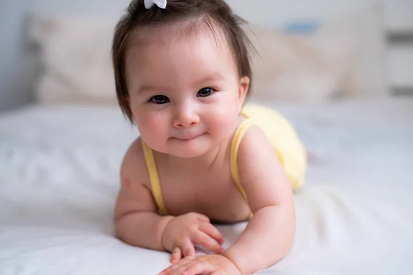 mixed ethnicity Asian Caucasian baby girl crawling on bed happy and curious - sweet and adorable little baby 8 months old with a funny pony tail exploring around cheerful