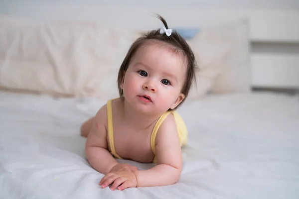 mixed ethnicity Asian Caucasian baby girl crawling on bed happy and curious - sweet and adorable little baby 8 months old with a funny pony tail exploring around cheerful
