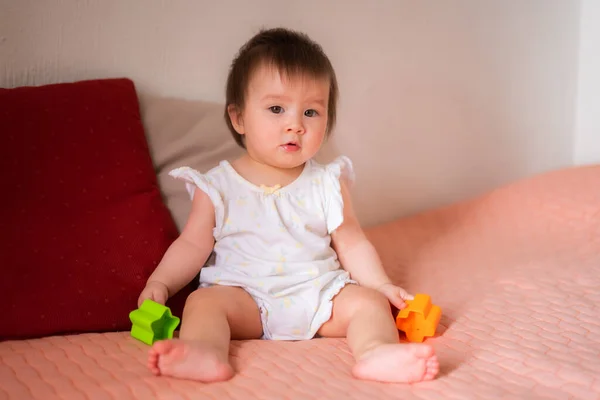 lifestyle home portrait of adorable and beautiful Asian Caucasian mixed baby girl playing on bed with color blocks excited and happy in childhood concept