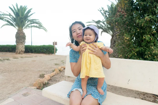亚洲母亲和她的小女儿的户外生活方式肖像 美丽的女人抱着他可爱快乐的小女儿在棕榈树公园享受暑假 — 图库照片