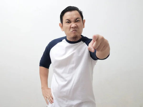 Young Asian man pointing to camera with angry cynical expression, giving warn. Against white background