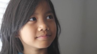 Portrait of Asian girl looking up and smiling, thinking expression gesture, close up