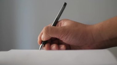 Close up of a person hand holding pen and writing on a book