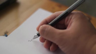 Close up of a person hand holding pen and writing on a book