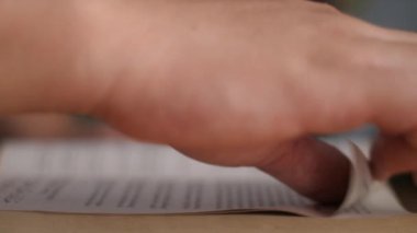 Close up side view of a person hand touching page when reading a book