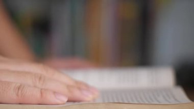 Close up side view of a person hand touching page when reading a book