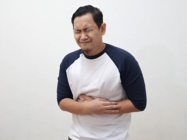 Young Asian man wearing white shirt having stomach ache. Close up body portrait