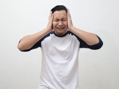Asyalı bir adam ağlıyor, gözlerini ve kulaklarını kapatıyor, üzgün depresyon hayal kırıklığı umutsuz bir ifade, beyaz arka plan için.