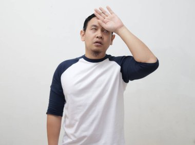 Genç Asyalı adam üşür ve ateşlenir, baş ağrısı hisseder. Ağrı azalır ve titrer, gri arka plana karşı.