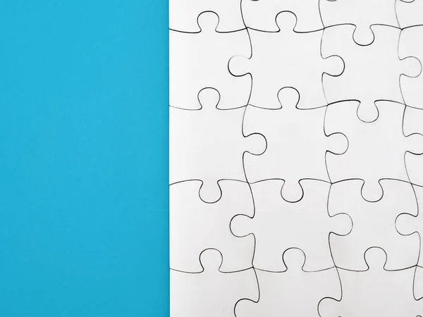 White jigsaw puzzle on blue background, top angle view layout