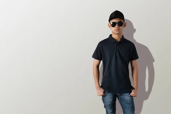 空の色のシャツモックアップテンプレート フロントビュー グレーの背景に無地の黒のTシャツを着てアジアの十代の男性モデル 印刷のためのポロティーデザインモックアッププレゼンテーション — ストック写真