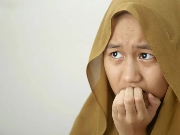 ヒジャーブを身に着けているアジアのイスラム教徒の十代の少女の肖像は 灰色の背景を背景に 彼女の爪をかむ 何か悪いのを心配し 恐れていた — ストック写真