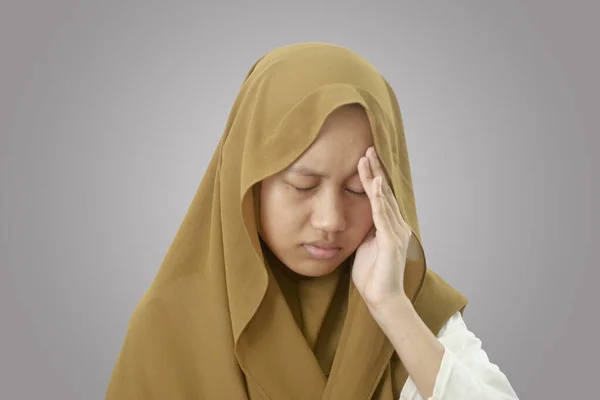 アジアのムスリムティーン女の子身に着けていますヒジャーブ保持彼女の頭に痛みのために持っています頭痛の種 クローズアップ肖像画に対して灰色の背景 — ストック写真