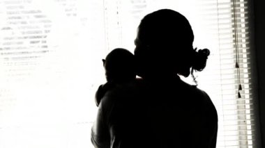 Annenin omzunda ağlayan küçük Asyalı bebek portresi. Siyah beyaz siluet.