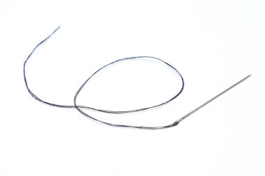 Beyaz arkaplan üzerinde siyah iplik ve iğne