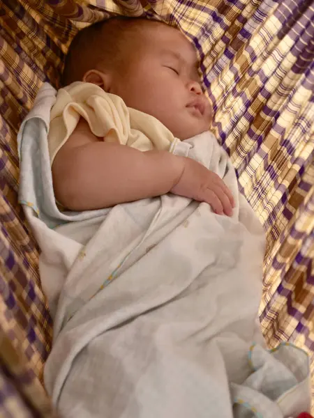 stock image Little Asian infant baby girl sleeping in traditional swinging fabric cradle