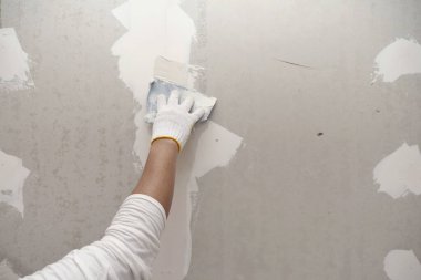 Sıva işi ve duvar boyası hazırlığı. Sıva uygulayan ya da alçıpan yamasını dolduran zanaatkârın elini kapat