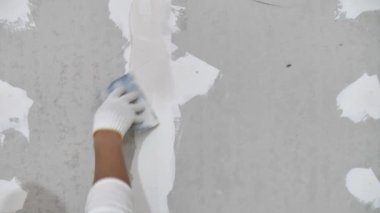 Sıva işi ve duvar boyası hazırlığı. Sıva uygulayan ya da alçıpan yamasını dolduran zanaatkârın elini kapat