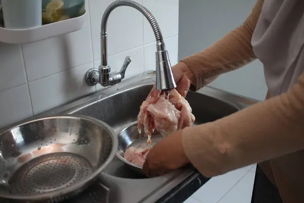 stock image Cooking in kitchen. Asian muslim woman washing and cleaning chicken meat after cutting. Meal preparation